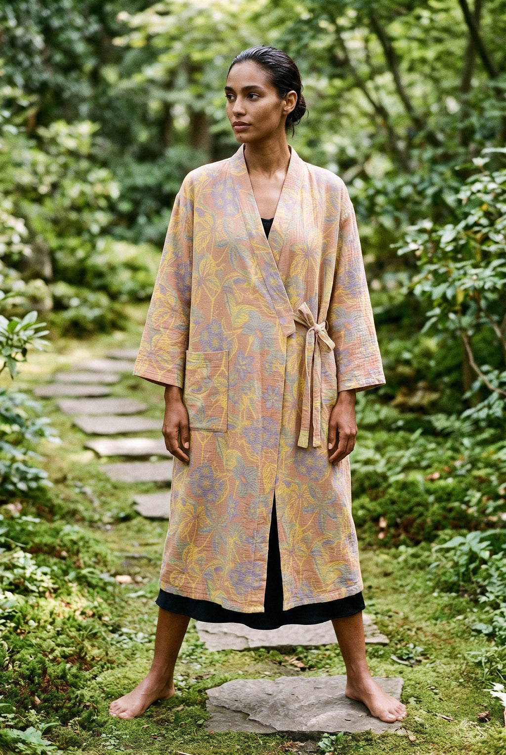 Bata kimono Kihada, jacquard botánico, melocotón: vista de frente, en un sendero de piedras en un jardín de musgo