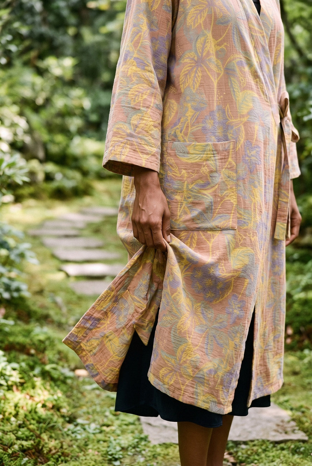 Bata kimono Kihada, jacquard botánico, melocotón: detalle del estampado y del tejido, en un sendero de piedras en un jardín de musgo