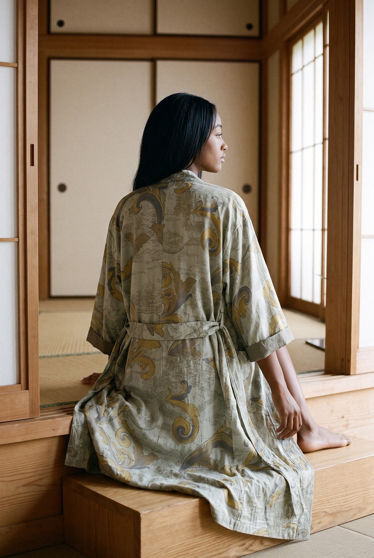 Bata kimono Mizuki, 100 % algodón, verde salvia: modelo de espaldas, sentada en un bloque, en una sala de té con tatamis
