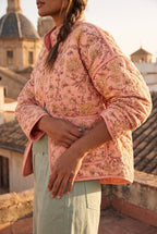 Chaqueta acolchada Benihana, flores, rosa salmón: detalle de la manga y del estampado, en una azotea de Valencia con vistas a las cúpulas