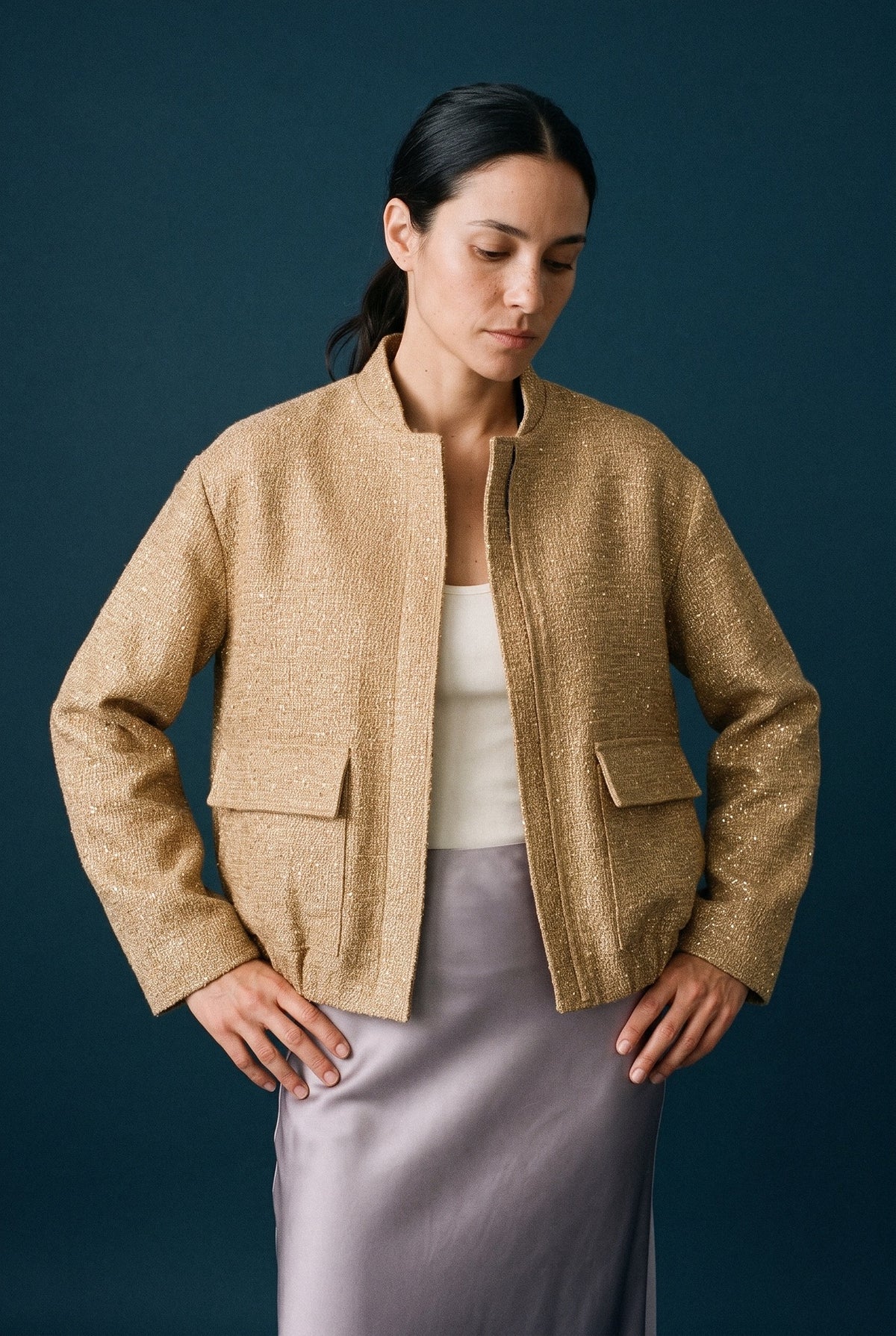 Chaqueta de lentejuelas Hoshi, cuello mao, dorado: vista de frente, en estudio, fondo azul petróleo