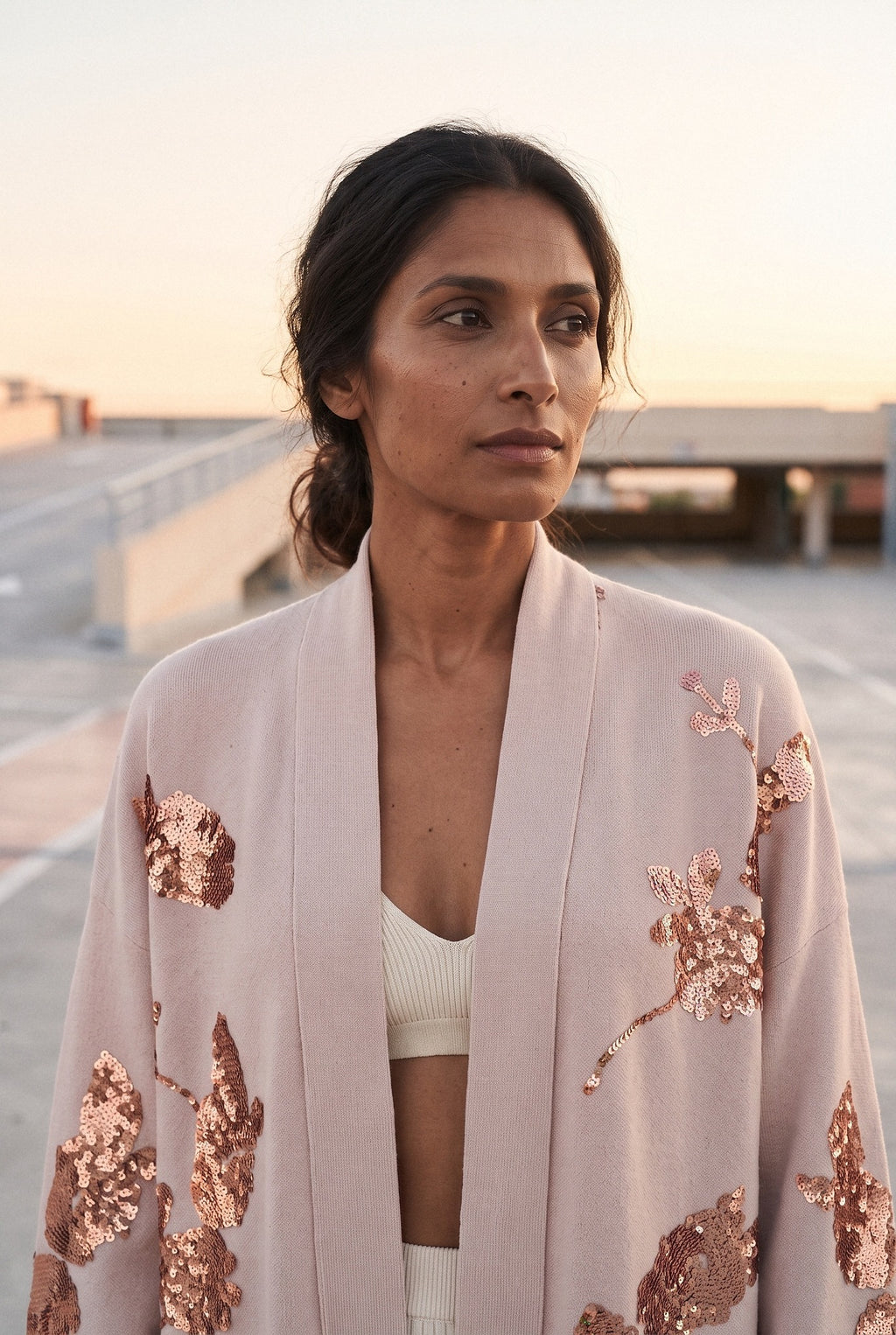 Chaqueta kimono Anzu, flores de lentejuelas, rosa empolvado: retrato de medio cuerpo, en la azotea de un aparcamiento de hormigón claro
