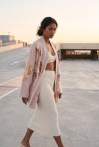 Chaqueta kimono Anzu, flores de lentejuelas, rosa empolvado: modelo caminando, vista de tres cuartos, en la azotea de un aparcamiento de hormigón claro