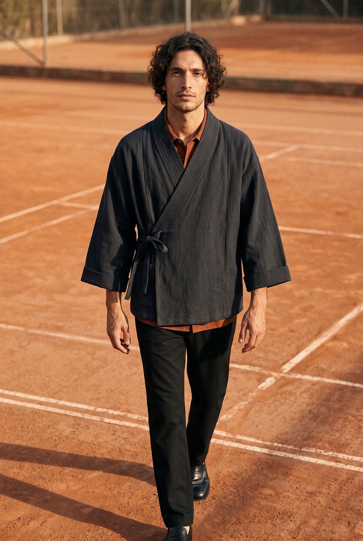 Chaqueta kimono Kenpō, algodón y lino, negro, hombre: modelo caminando hacia la cámara, en una pista de tenis de tierra batida