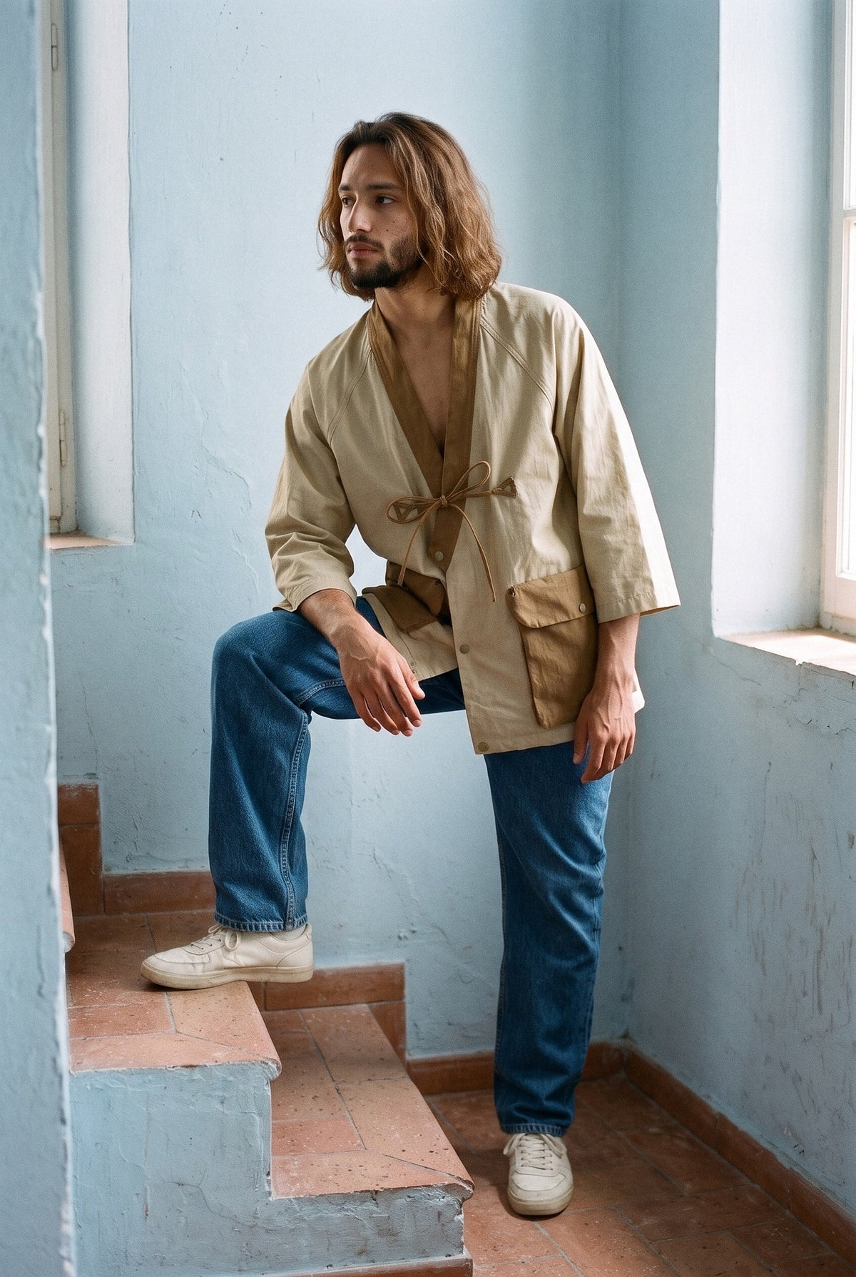 Chaqueta kimono Noragi, estilo workwear, caqui o azul marino: modelo con un pie en un escalón, en una escalera luminosa de paredes azul pálido