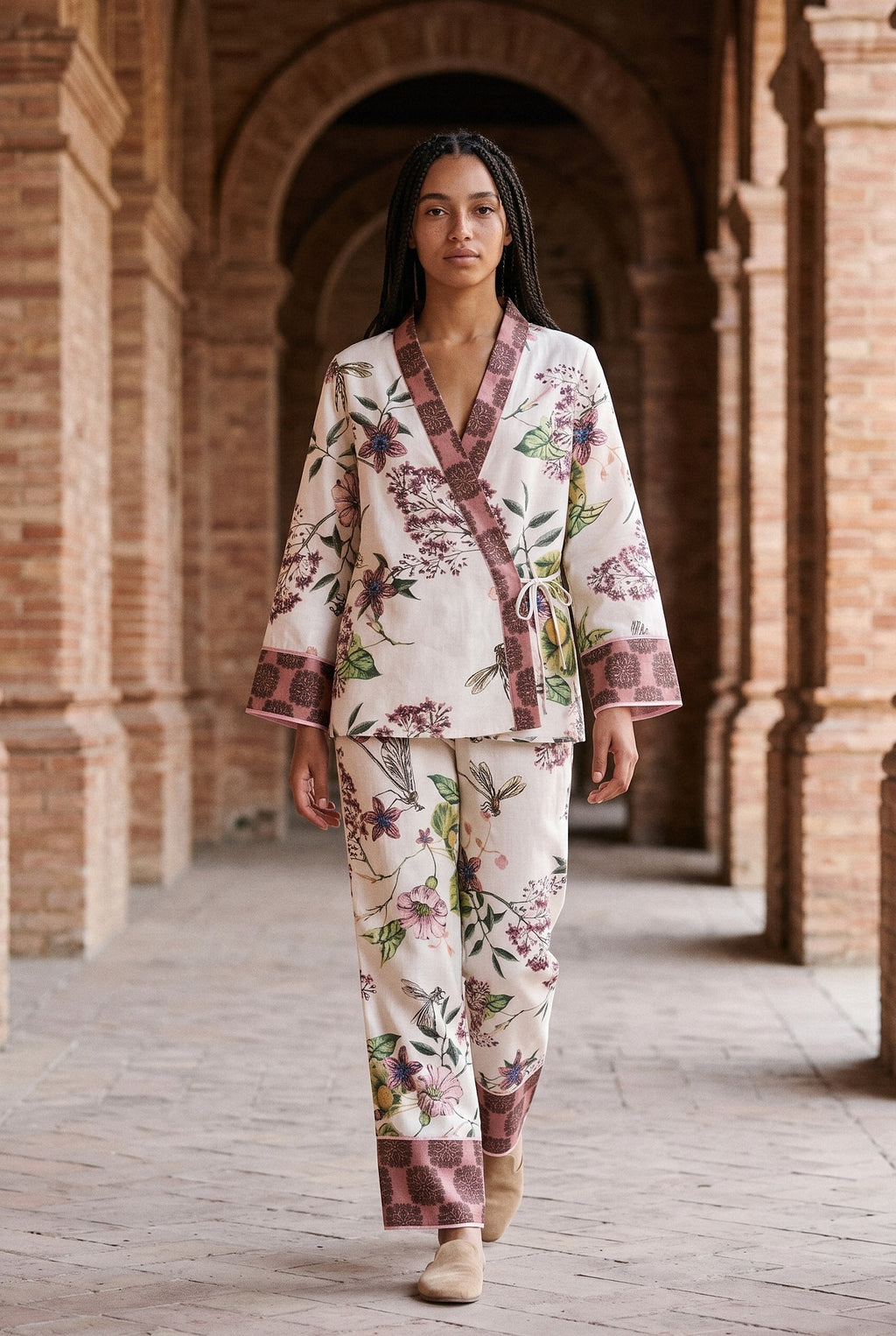 Conjunto kimono Haru, flores y libélulas, crudo: modelo caminando hacia la cámara, bajo los arcos de ladrillo de una antigua fábrica de Sevilla