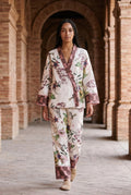 Conjunto kimono Haru, flores y libélulas, crudo: modelo caminando hacia la cámara, bajo los arcos de ladrillo de una antigua fábrica de Sevilla