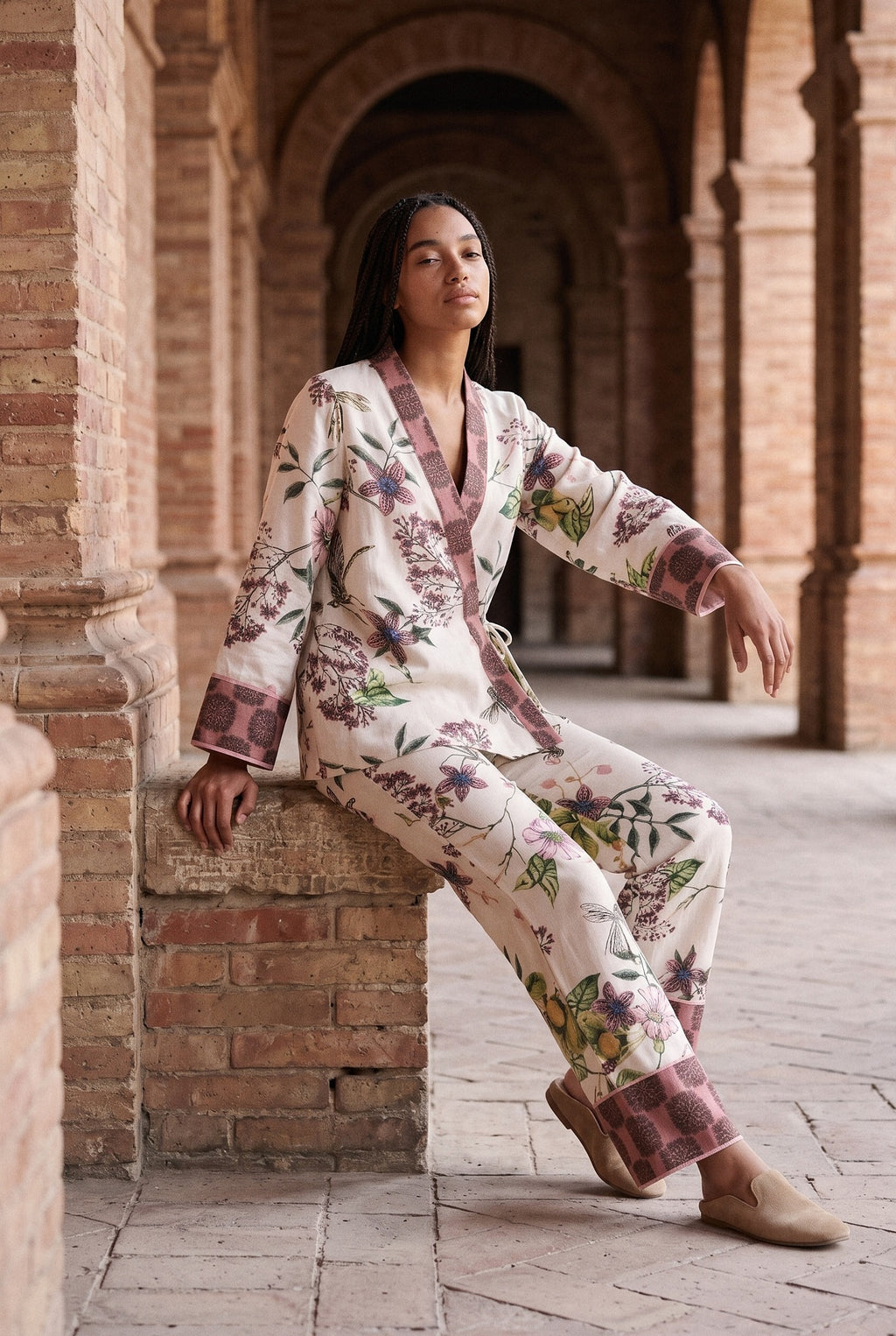 Conjunto kimono Haru, flores y libélulas, crudo: modelo sentada con una pierna estirada, bajo los arcos de ladrillo de una antigua fábrica de Sevilla