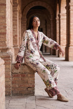 Conjunto kimono Haru, flores y libélulas, crudo: modelo sentada con una pierna estirada, bajo los arcos de ladrillo de una antigua fábrica de Sevilla