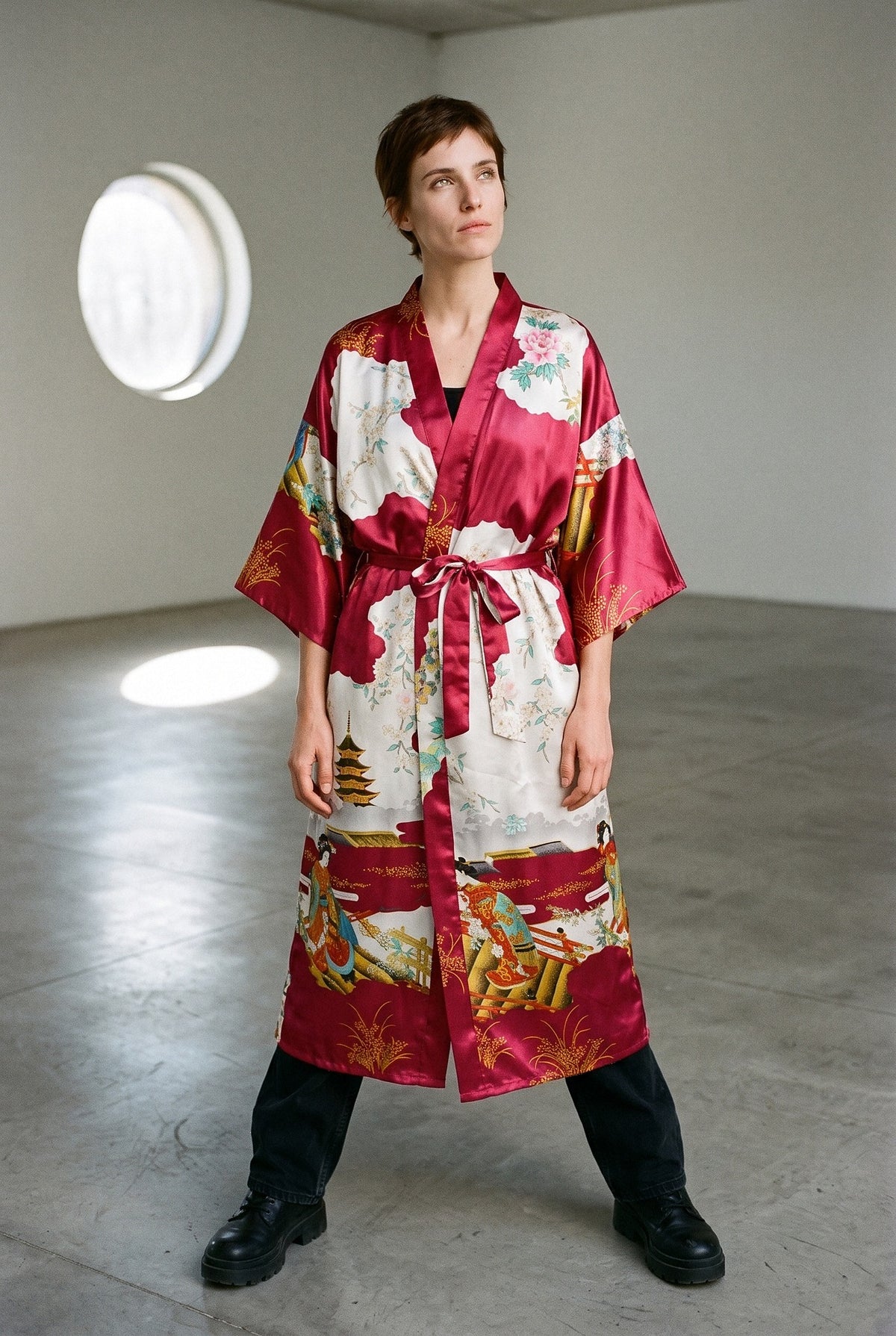 Kimono Beni, satinado rojo con motivos japoneses: vista de frente, en una galería de arte moderna con ventana redonda