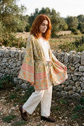Kimono corto Asahi, flores, verde salvia: modelo caminando, junto a un muro de piedra seca en Mallorca
