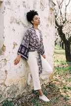 Kimono corto Hai, flores, azul marino y rosa: modelo apoyada en la pared, en un almendral en flor de Mallorca