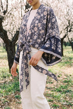 Kimono corto Hai, flores, azul marino y rosa: detalle del estampado y del tejido, en un almendral en flor de Mallorca
