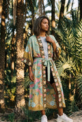 Kimono largo Koke, pavo real y flores, verde salvia: vista de frente, en un palmeral de Elche