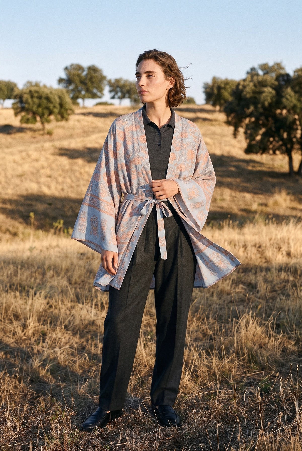 Kimono corto Kumori, flores, azul grisáceo: modelo con el tejido movido por la brisa, en una dehesa dorada de Salamanca