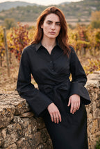 Kimono corto Musubi, blusa cruzada con lazo, negro: modelo apoyada en un muro, en un viñedo de La Rioja en otoño