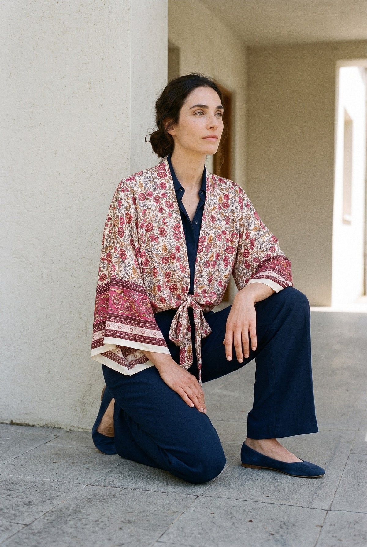 Kimono corto Persia, jardín persa, beige: modelo con una rodilla en el suelo, en el porche en sombra de una casa blanca minimalista