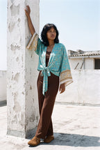 Kimono corto Wakaba, flores, turquesa: modelo con un brazo en alto, en una azotea blanca de Cádiz