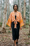 Kimono corto Yamabuki, flores, marfil y naranja: modelo caminando hacia la cámara, en un bosque de eucaliptos de Cantabria