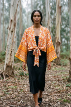 Kimono corto Yamabuki, flores, marfil y naranja: modelo caminando hacia la cámara, en un bosque de eucaliptos de Cantabria