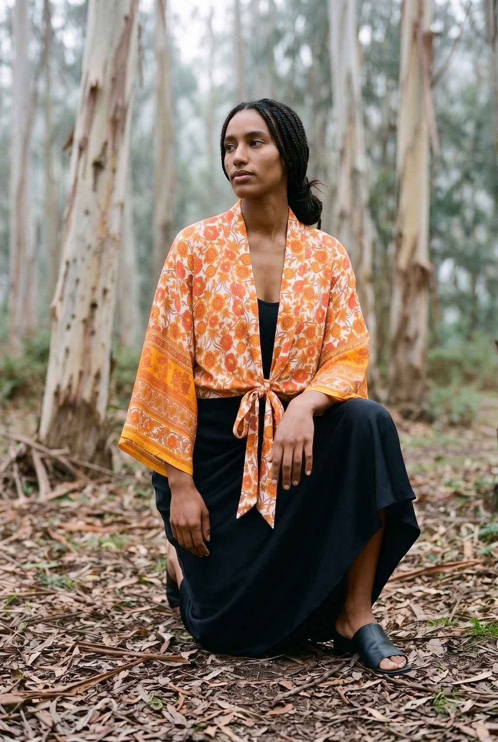 Kimono corto Yamabuki, flores, marfil y naranja: modelo con una rodilla en el suelo, en un bosque de eucaliptos de Cantabria