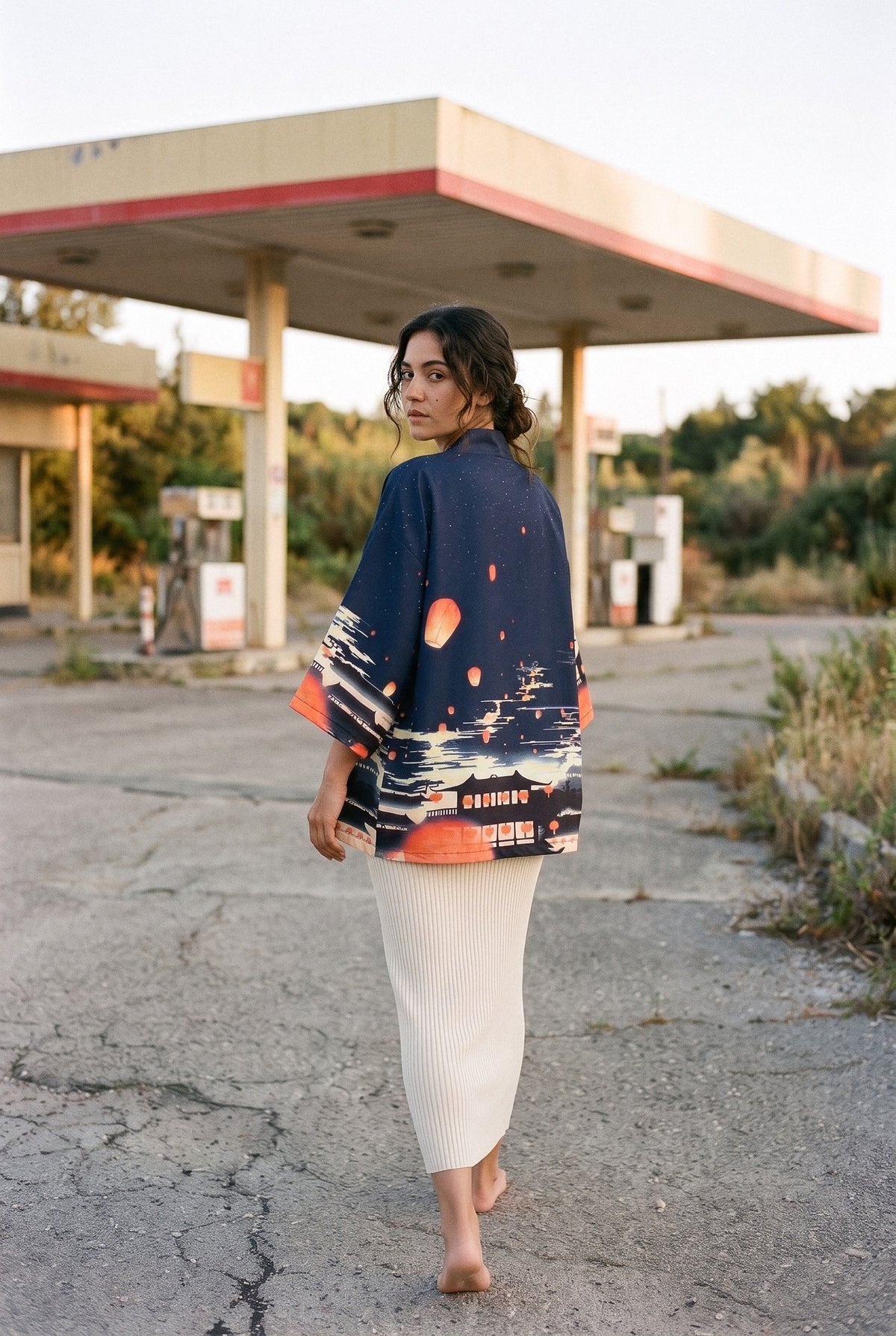 Kimono japonés Chōchin, linternas y ciudad, azul noche: modelo de espaldas, mirando por encima del hombro, bajo la marquesina de una gasolinera de los años 60