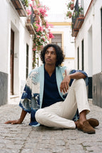 Kimono japonés Kanagawa, olas y remolino, azul: modelo sentado en el suelo, en un callejón de Sevilla con buganvillas