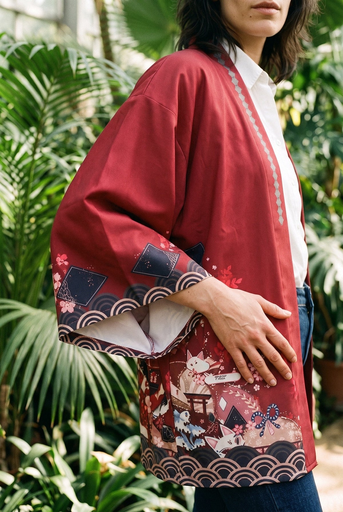 Kimono japonés Shu, grullas y flores, rojo carmín: detalle de la manga y del estampado, en un invernadero de jardín botánico con plantas tropicales