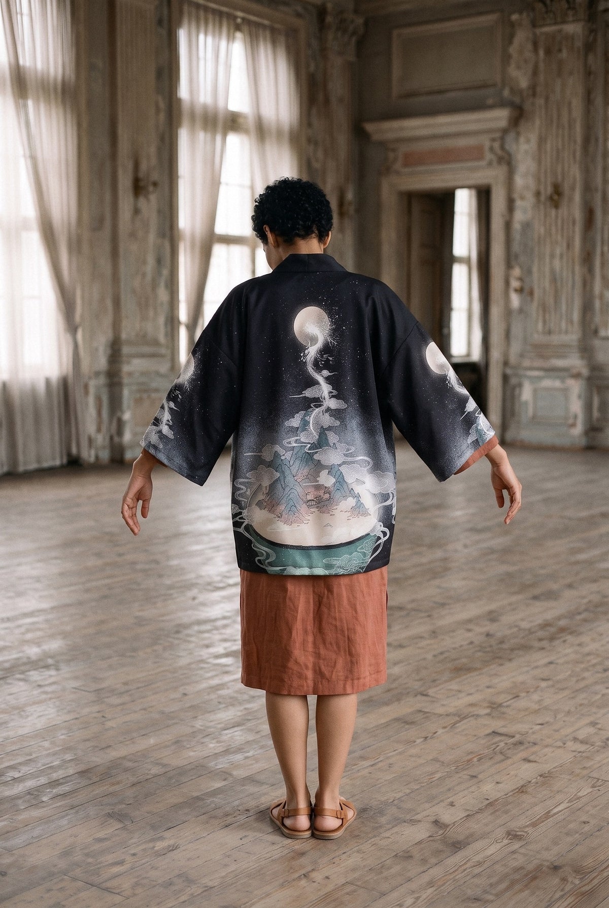 Kimono japonés Tsuki no Ryū, dragón y luna, negro: modelo de espaldas, con los brazos abiertos que despliegan las mangas, en un antiguo salón de baile con suelo de madera