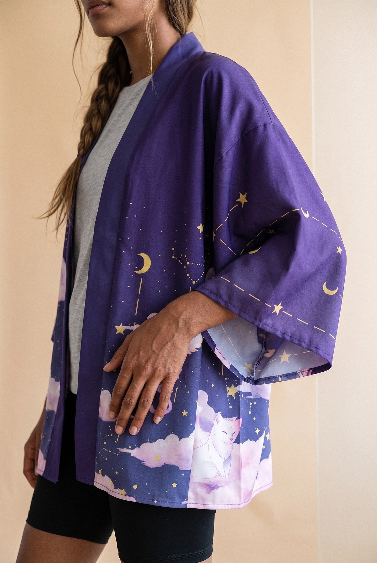 Kimono japonés Yozora, gatos y nubes, violeta noche: detalle de la manga y del estampado, en estudio, fondo beige arena con cristal esmerilado
