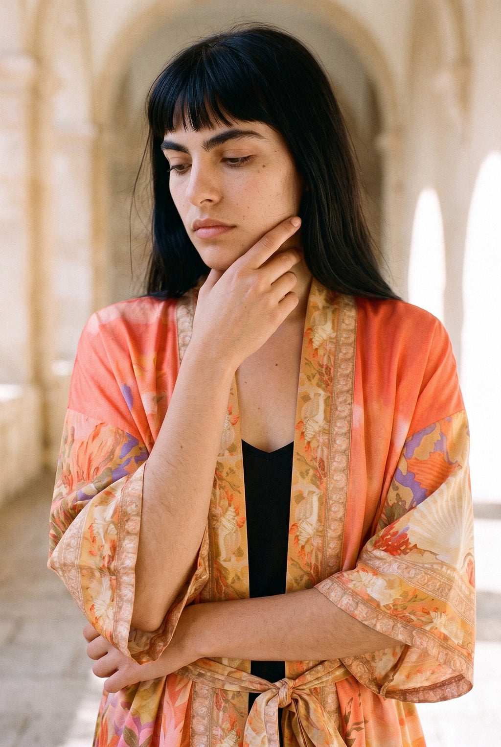 Kimono largo Sangoshō, flores, coral: retrato, mano en la barbilla, en un claustro de arcos de arenisca