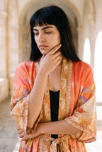 Kimono largo Sangoshō, flores, coral: retrato, mano en la barbilla, en un claustro de arcos de arenisca