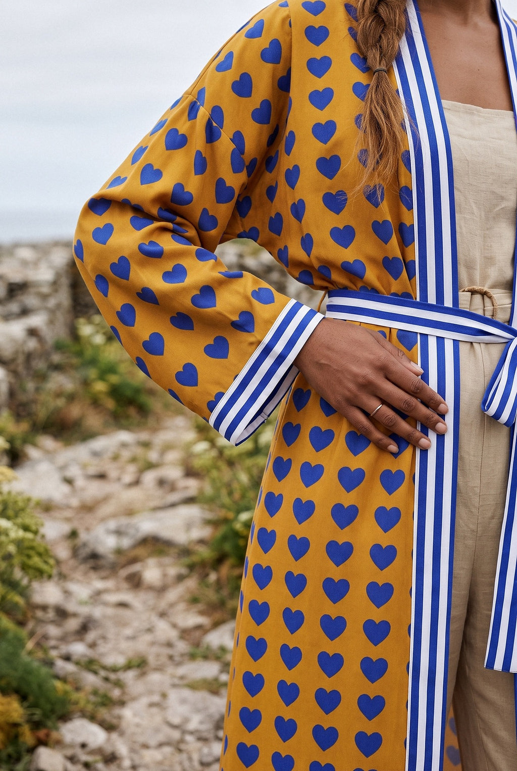 Kimono largo Shimauma, corazones azules, amarillo: detalle de la manga y del estampado, en un sendero costero de Galicia