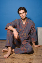 Pijama kimono Momiji, chaqueta y pantalón, azul marino: modelo sentado en el suelo, en estudio, fondo azul cobalto