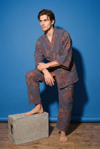 Pijama kimono Momiji, chaqueta y pantalón, azul marino: modelo con un pie en un escalón, en estudio, fondo azul cobalto