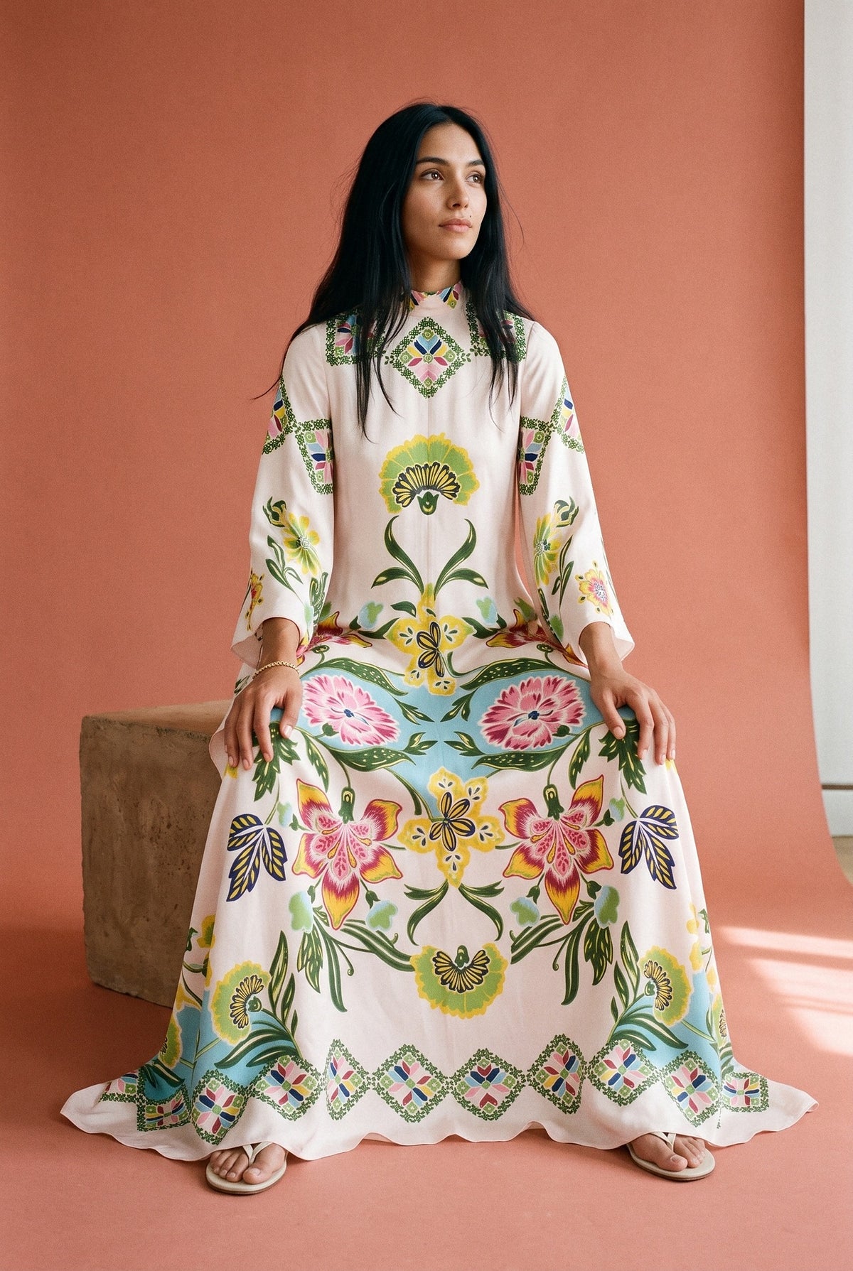 Vestido kimono Niwa, estampado crudo floral: modelo sentada en un bloque, en estudio, fondo rosa terracota