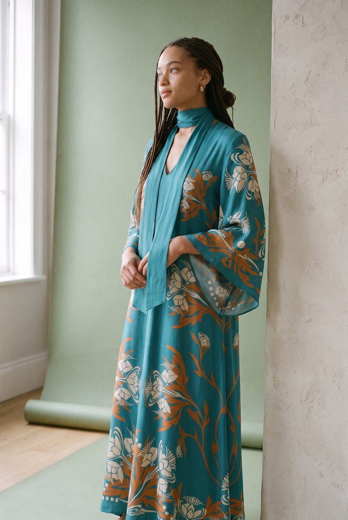 Vestido kimono Seiji, estampado turquesa: modelo con las manos dentro de las mangas, en estudio, fondo verde salvia